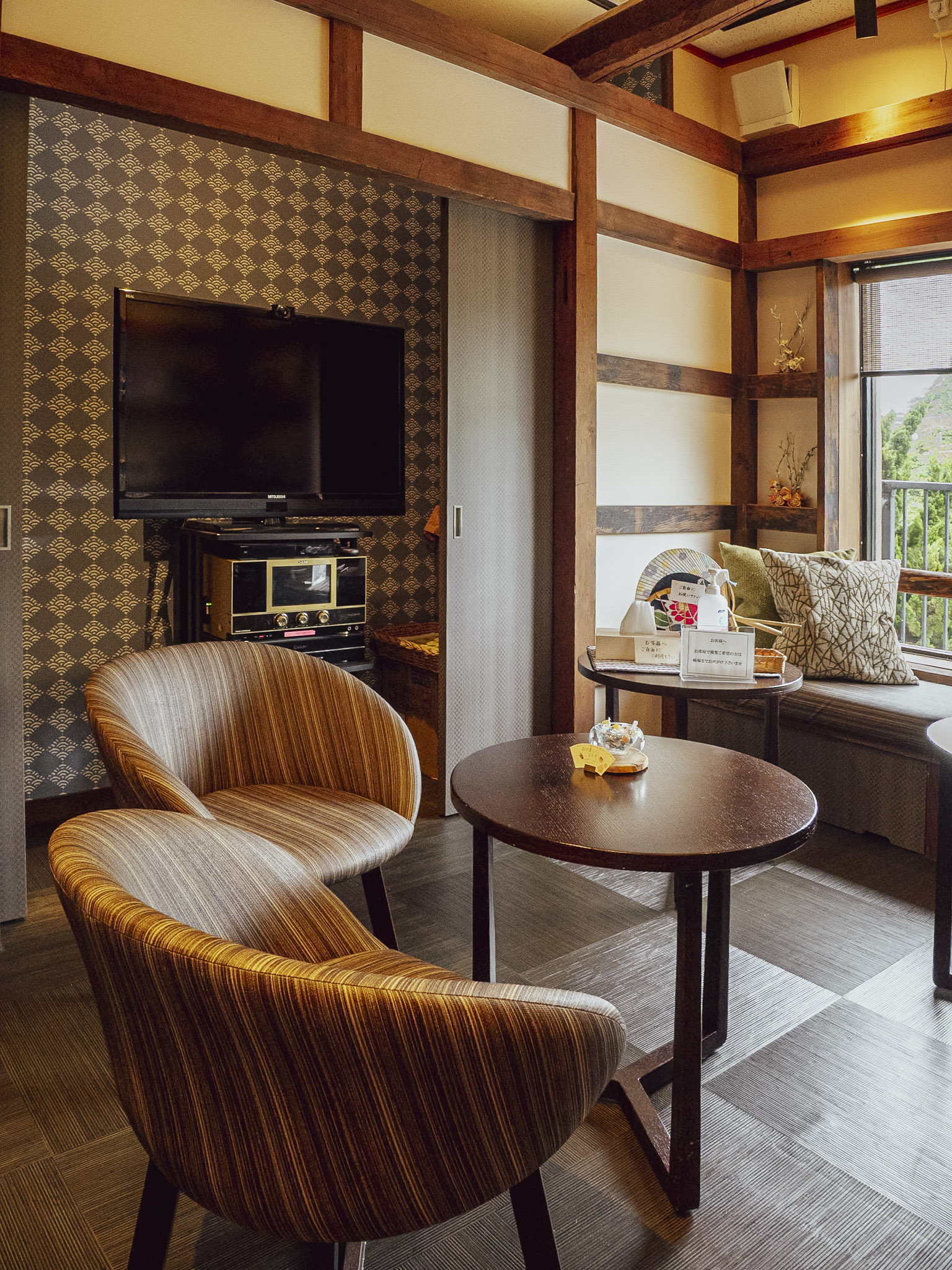 Japanese-style lounge with armchairs and a TV at Hotel Sunosaki Kazenosho in Tateyama, Chiba